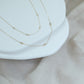 14ct recycled gold diamond bracelet and necklace on white stones with a linen background