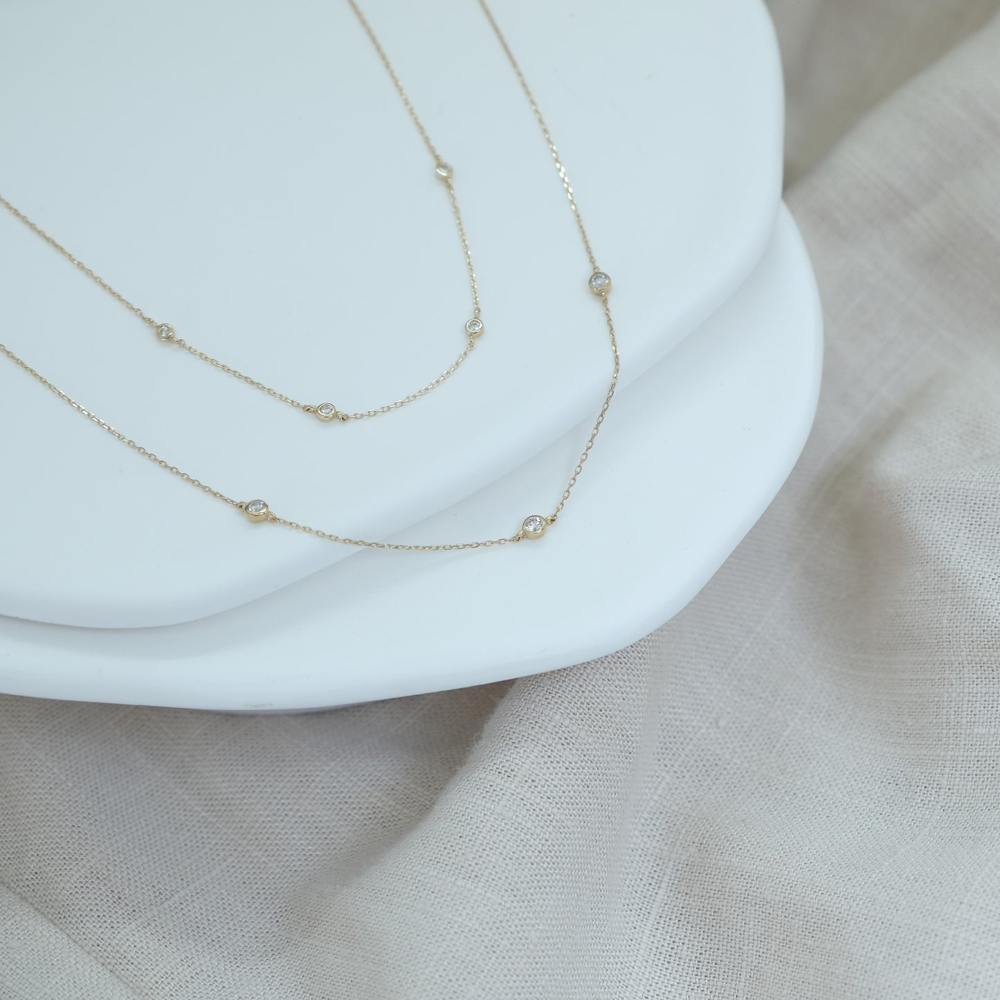 14ct recycled gold diamond bracelet and necklace on white stones with a linen background